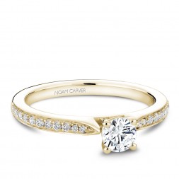 A solitaire Carver Studio yellow gold engagement ring with a round center stone and 23 diamonds.
